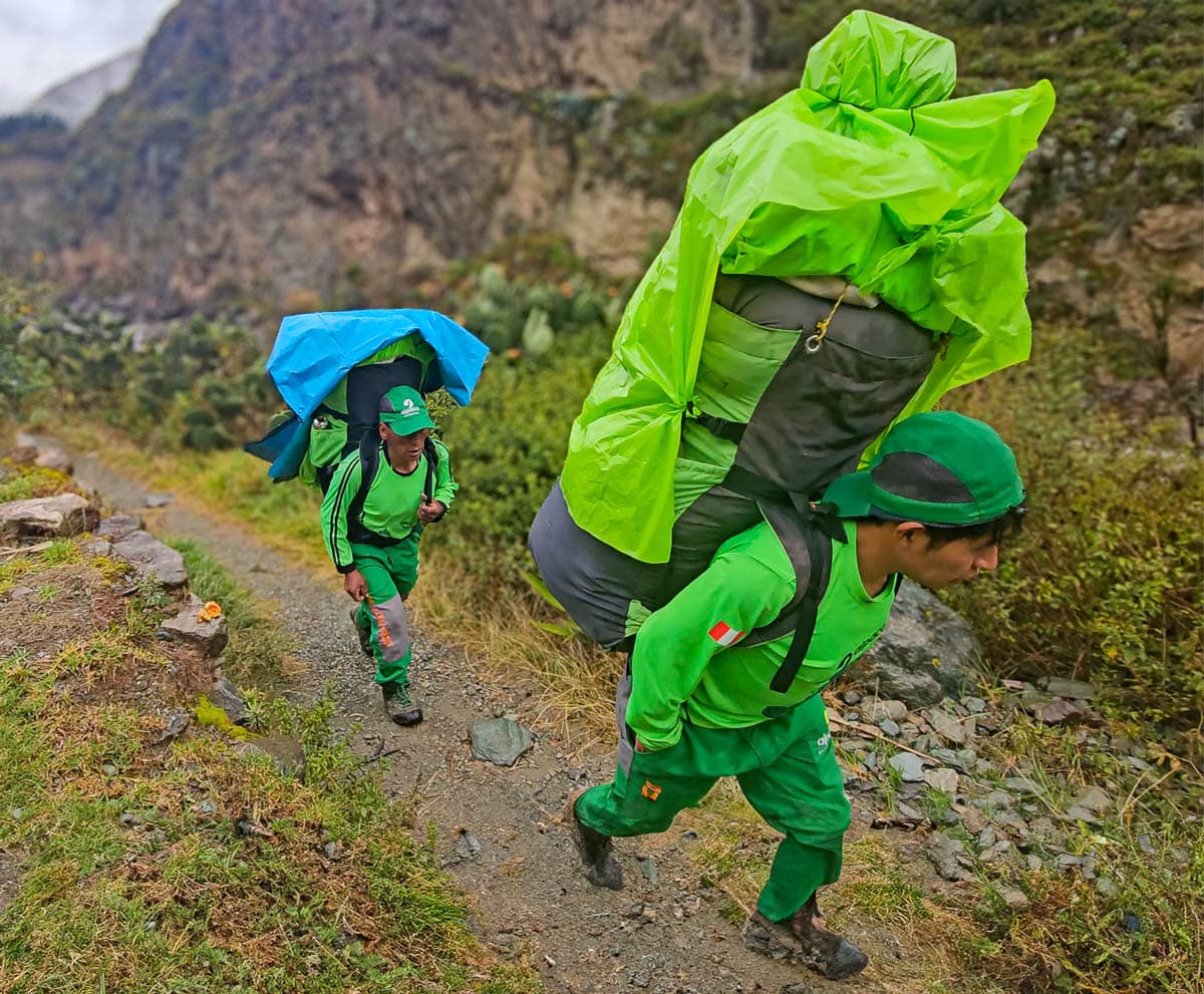 Porters hiking with large backpacks along the Inca Trail in Peru