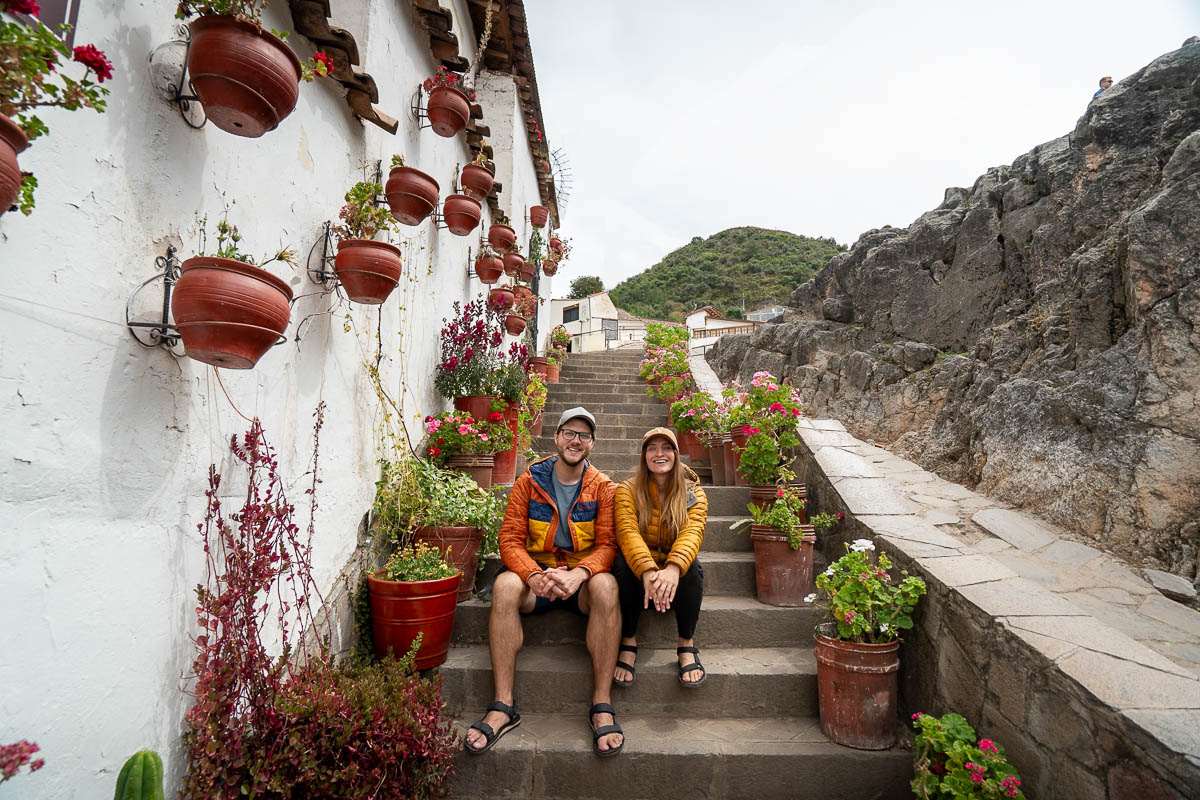 Couple sitting on a staircase with flowerpots lining a wall in the San Bas neighborhood of Cusco, Peru