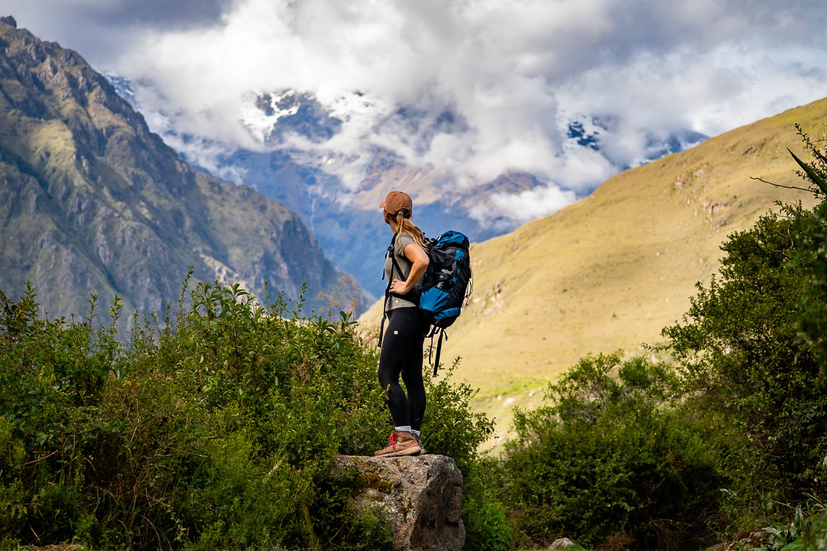 Woman standing on a rock with Andes mountains in the background of the Inca Trail in Peru