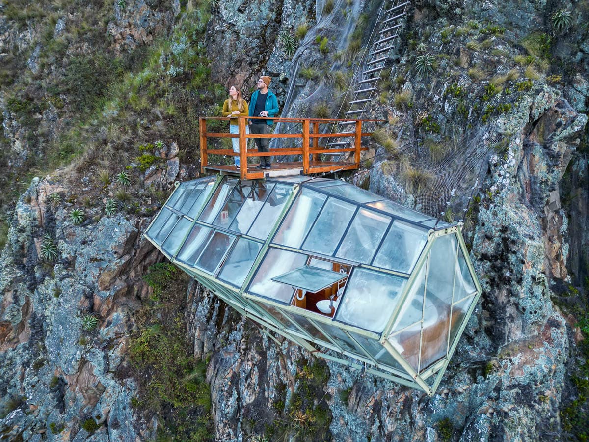 Couple standing on a wooden balcony on top of glass capsule at the the Vertical Sky Suites in Ollytantambo of the Sacred Valley of Peru