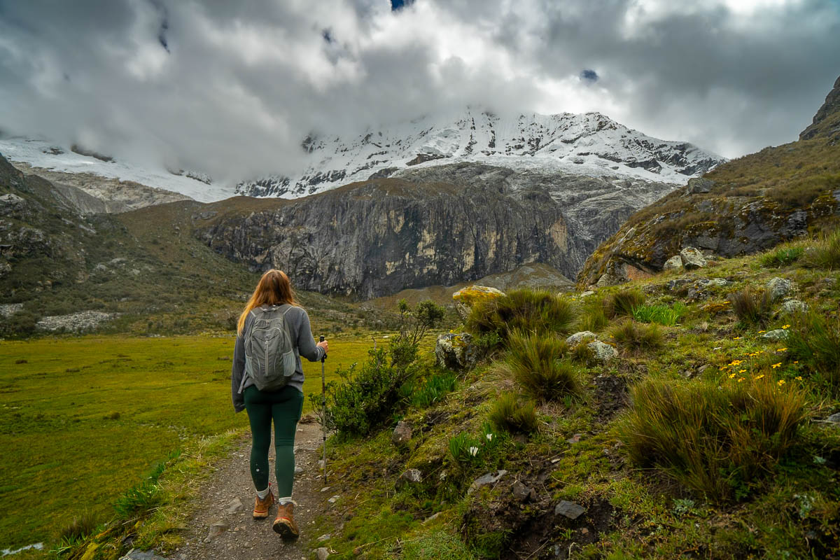 Woman hiking on the Laguna 69 trail with a snowy mountain in front of her in Huascarán National Park in Peru