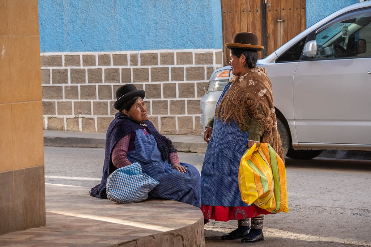 Two cholita women talking on a street corner in Copacabana, Bolivia