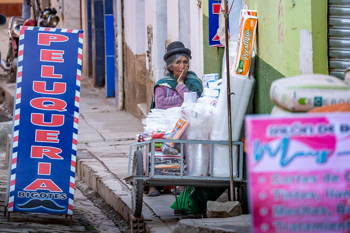 Woman in traditional Bolivian clothing sitting at a cart in Copacabana, Bolivia