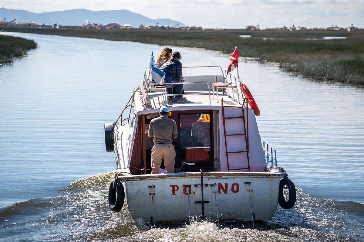 Boat with tourists navigating through reeds to the Uros islands near Puno, Peru