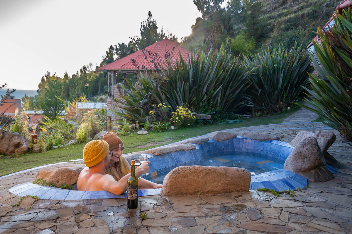 Couple sitting in a sunken hot tub with Lake Titicaca in the background in Copacabana, Bolivia