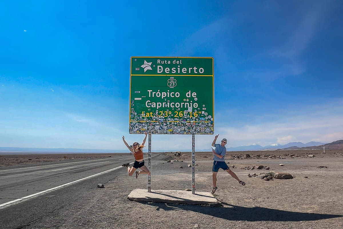 Couple jumping in front of Tropico de Capricornio near San Pedro de Atacama, Chile