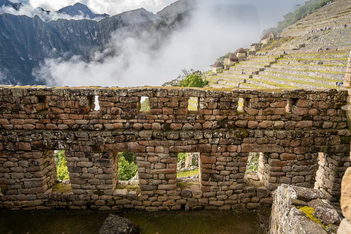 Inca ruins with agricultural terraces, moody clouds, and mountains in the background in Machu Picchu, Peru