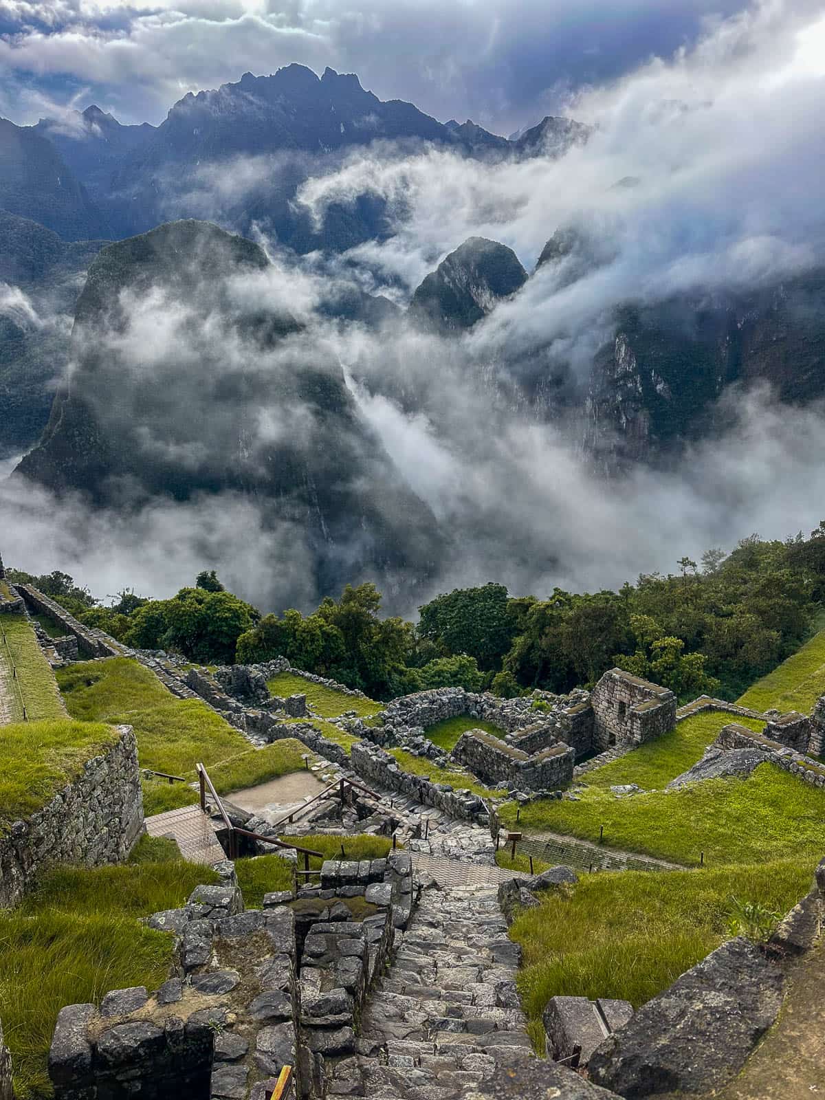 Inca ruins with moody clouds and mountains in the background in Machu Picchu, Peru