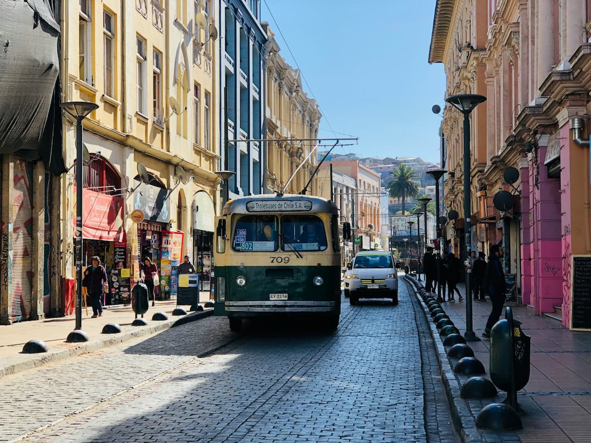 Cable car riding along a cobblestone street between colorful buildings in Valparaiso, Chile