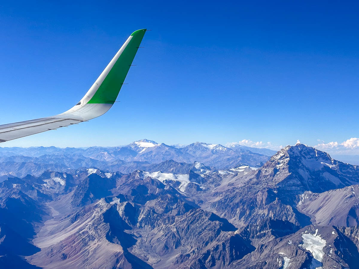 Airplane wing over the snow-capped Andes Mountains in Chile