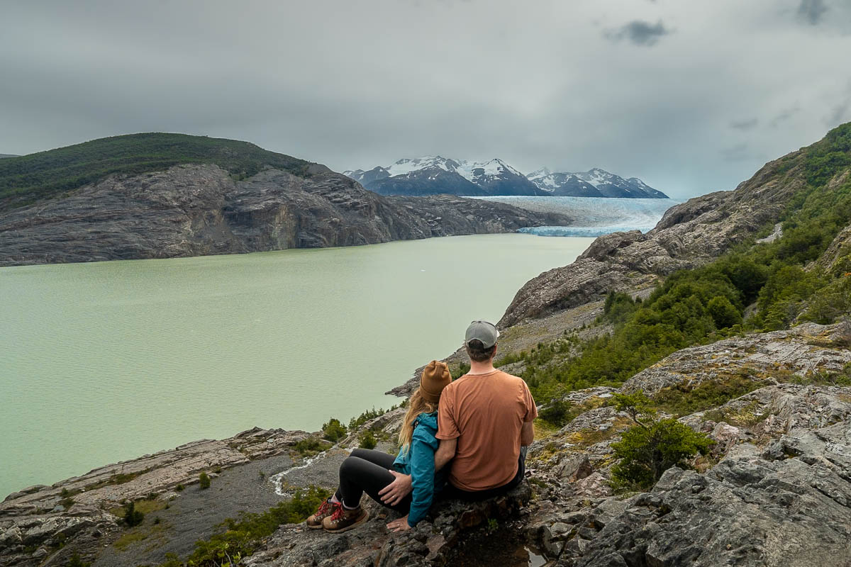 Couple sitting at the Mirador Lago Grey, looking at Glacier Grey in Torres del Paine National Park in Chile