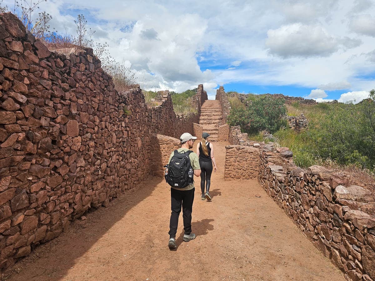 Couple walking between stone walls of Pikillata ruins near Cusco, Peru