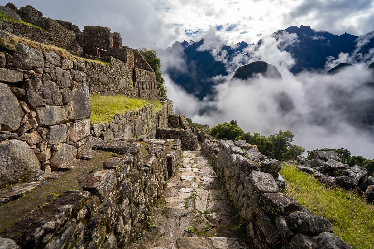 Inca ruins in Machu Picchu with moody clouds and mountains in the background in the Andes Mountain of Peru
