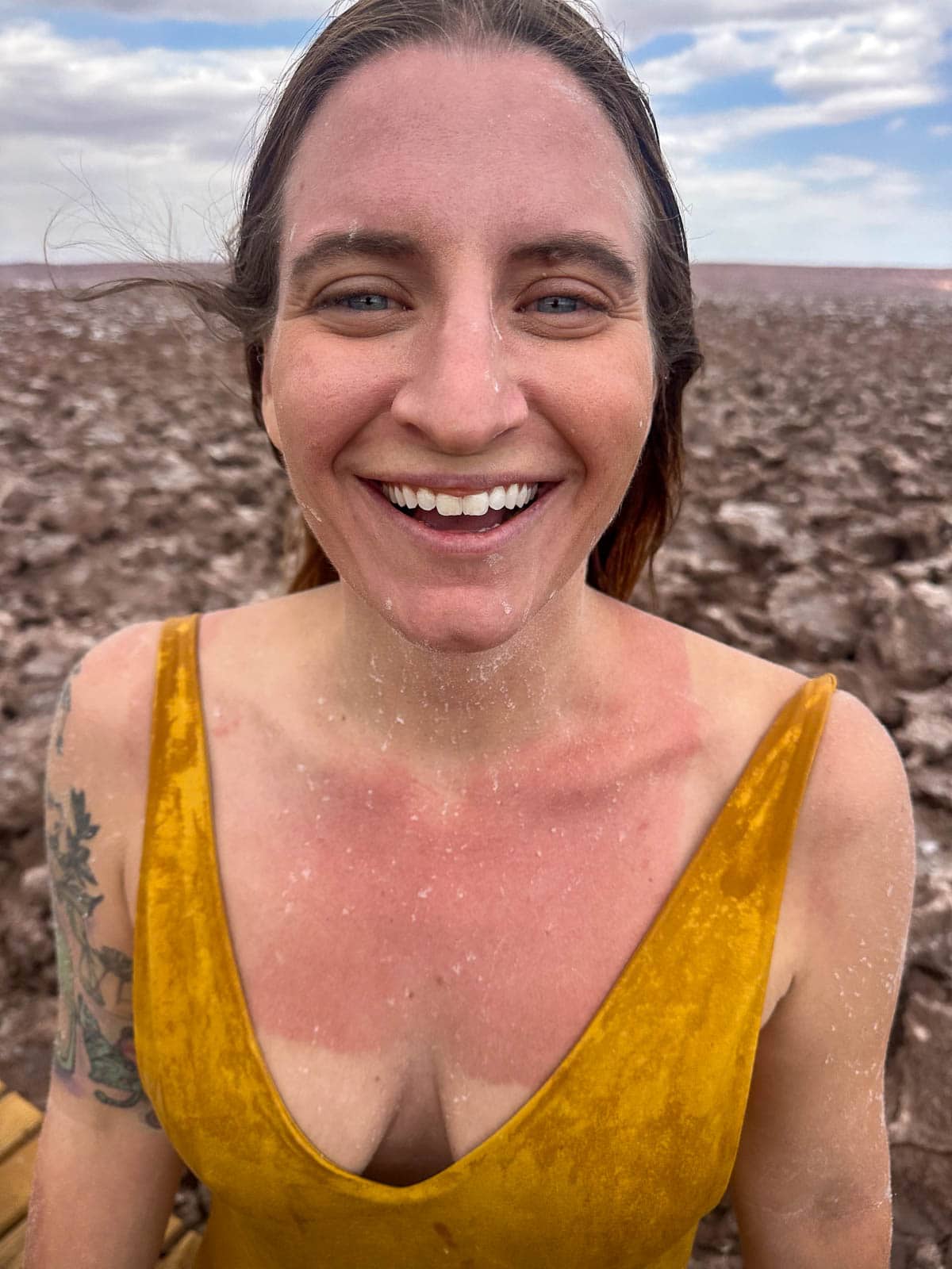 Smiling woman covered with salt after getting out of a salt lagoon at Lagunas Escondidas de Baltinache in San Pedro de Atacama in the Atacama Desert, Chile