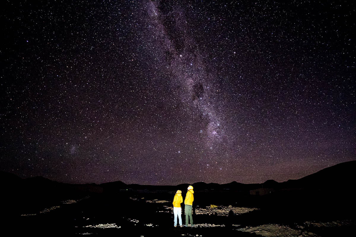 Couple looking up at a starry sky with the Milky Way above in the Atacama Desert in Chile
