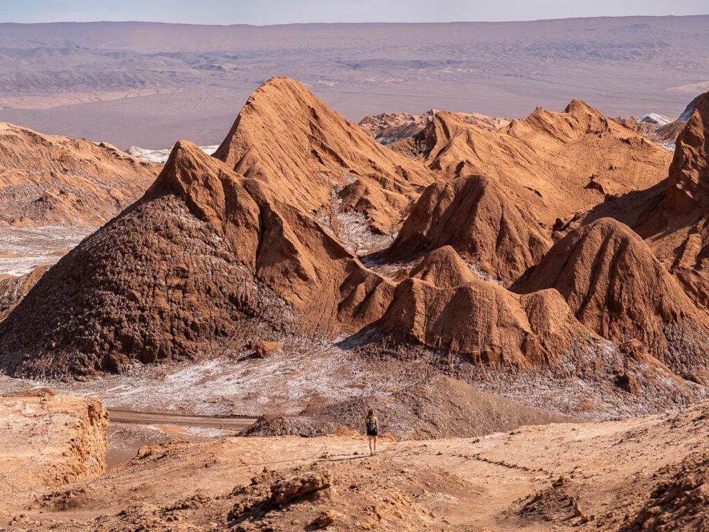 Woman standing on a ridge with rock formations in the background in Valle de la Luna near San Pedro de Atacama in the Atacama Desert