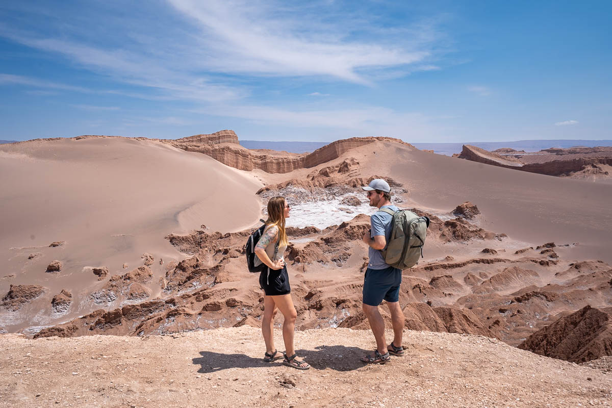 Couple looking at each other in front of a rock formation covered in sand dunes in Valle de la Luna near San Pedro de Atacama in the Atacama Desert in Chile