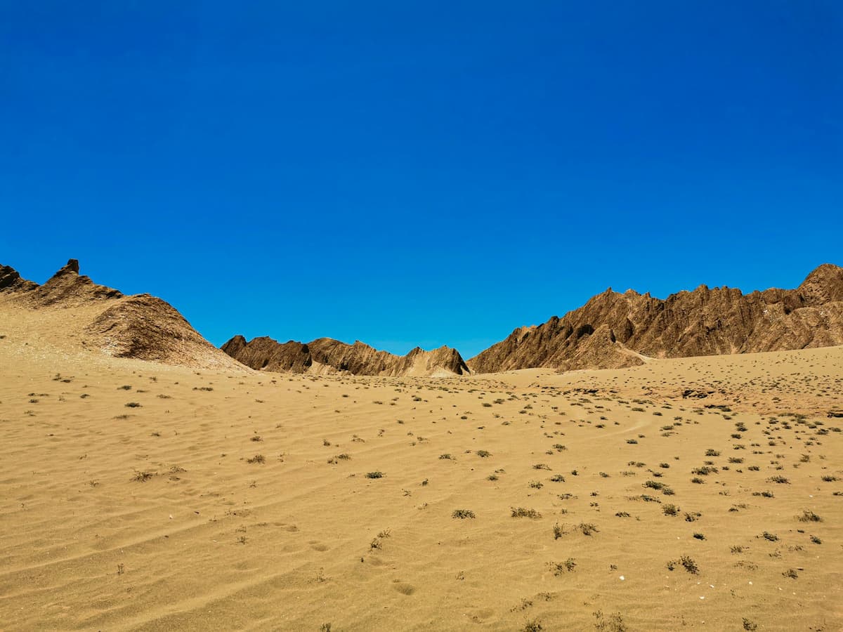 Sand dunes with rock formations in the background in Valle de Martes near San Pedro de Atacama in the Atacama Desert in Chile