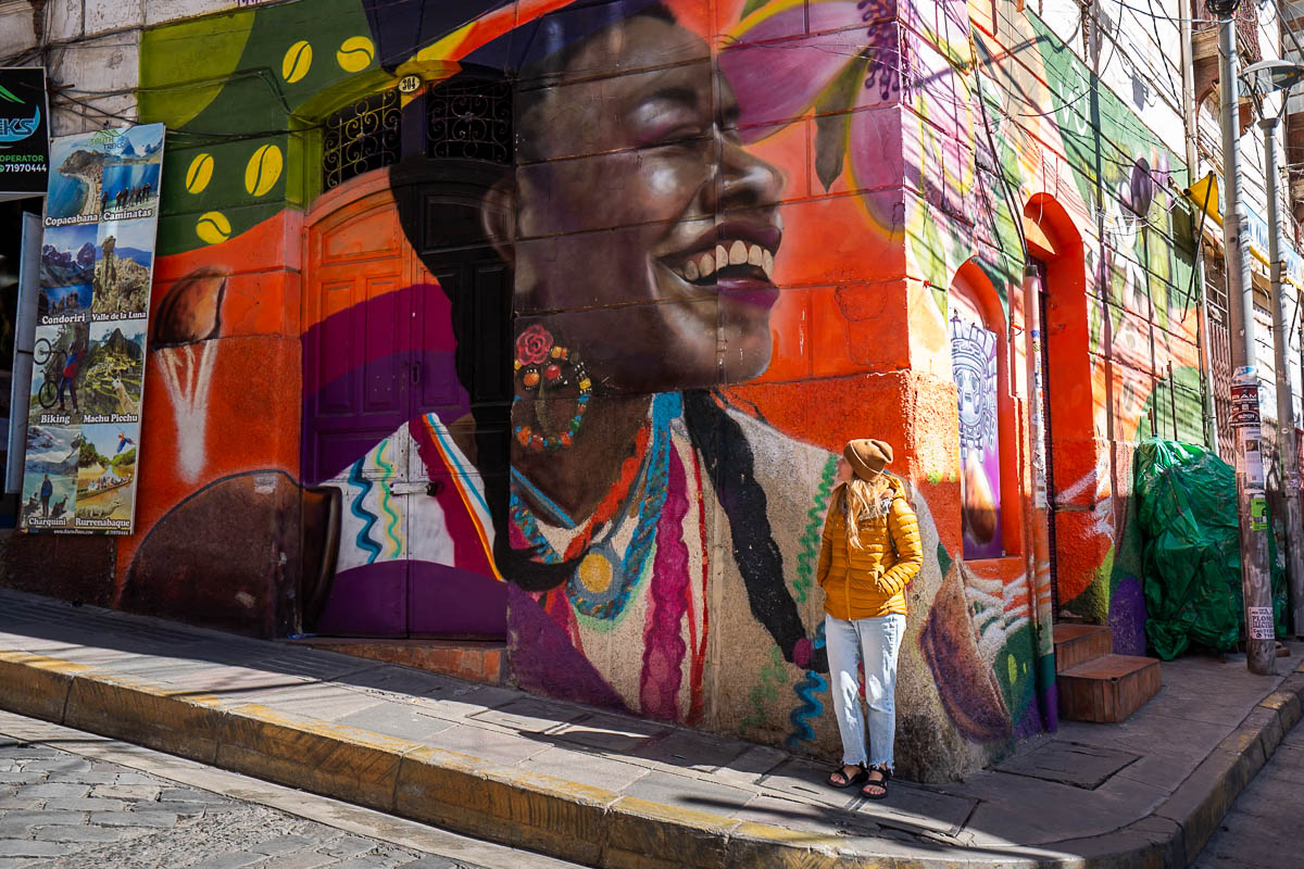 Woman standing near a colorful mural by the Witch's Market in La Paz, Bolivia