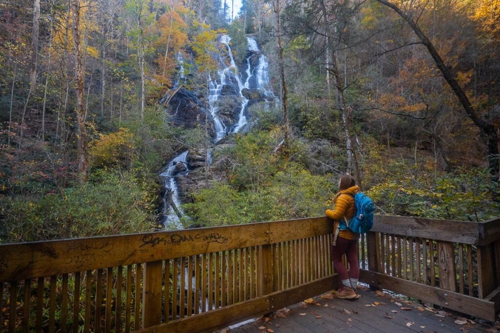 Woman standing on a wooden observation platform looking at Dukes Creek Falls along the Dukes Creek Falls Trail near Helen, Georgia