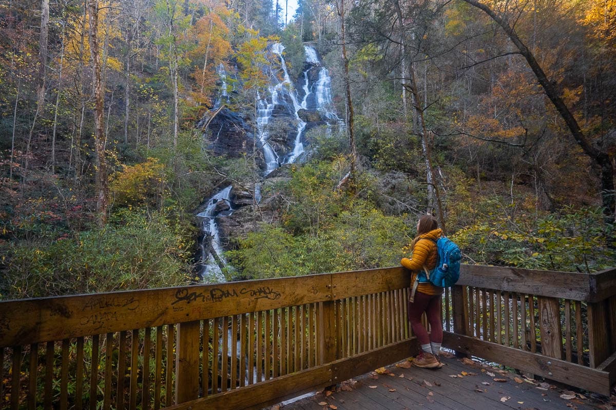 Woman standing on a wooden observation platform looking at Dukes Creek Falls along the Dukes Creek Falls Trail near Helen, Georgia