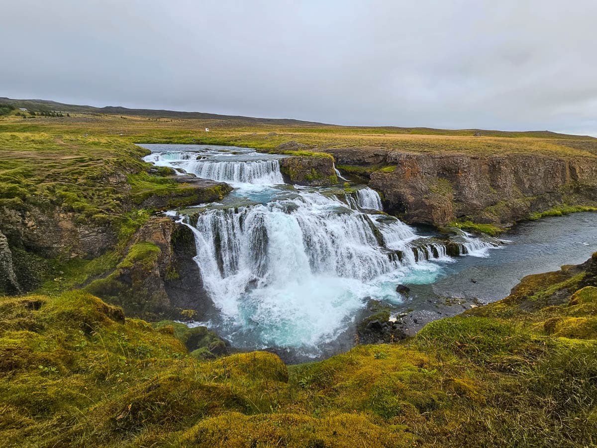 Reykjafoss waterfall spilling over a cliffside in farmland along the Huseyjarkvisl River in Iceland