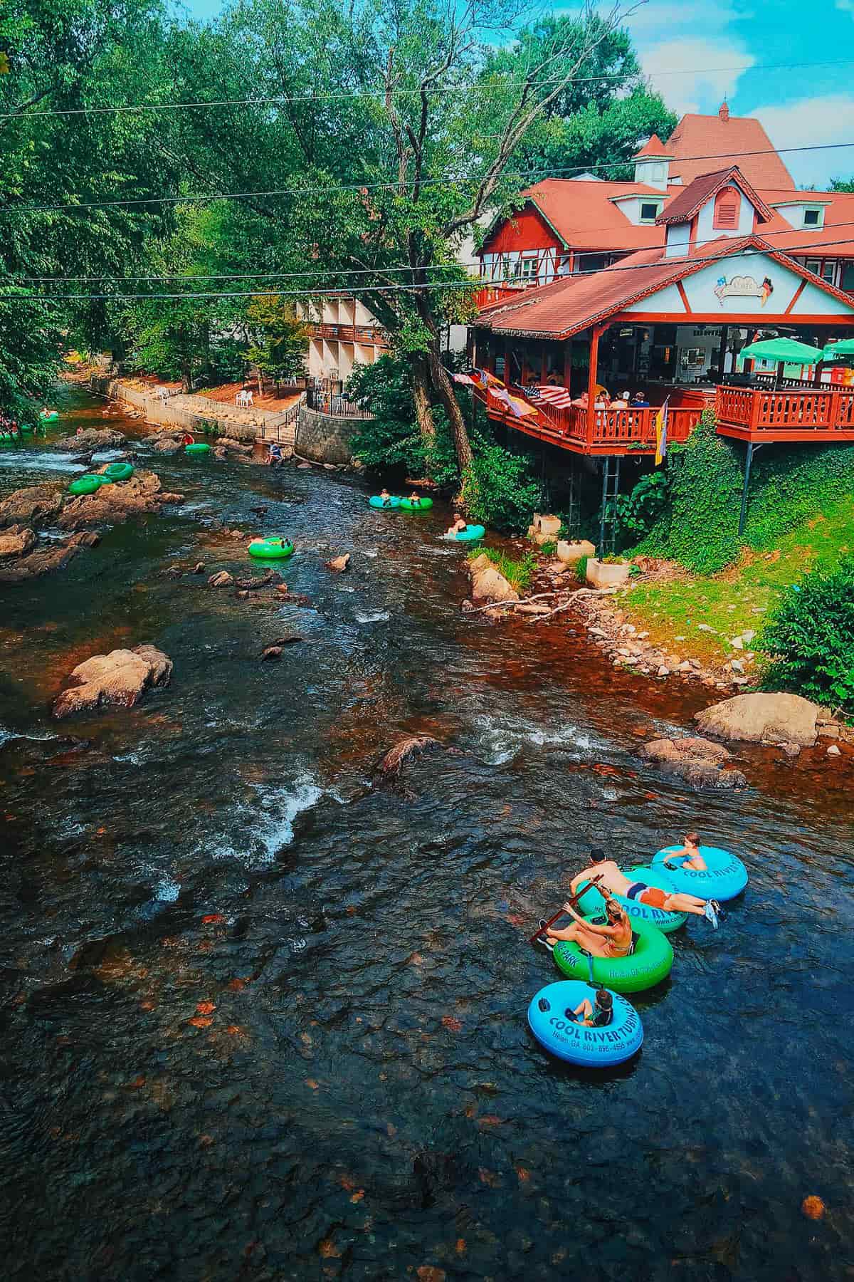 People tubing down Chattahoochee River past Cafe International in Helen, Georgia