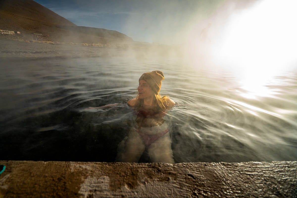 Woman soaking in the Polques Hot Springs with a steamy background near Uyuni, Bolivia