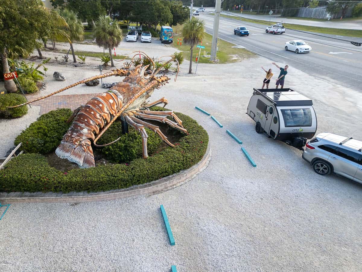 Couple standing on an RV next to a giant lobster statue at Rainbarrel Village in Islamorada in the Florida Keys