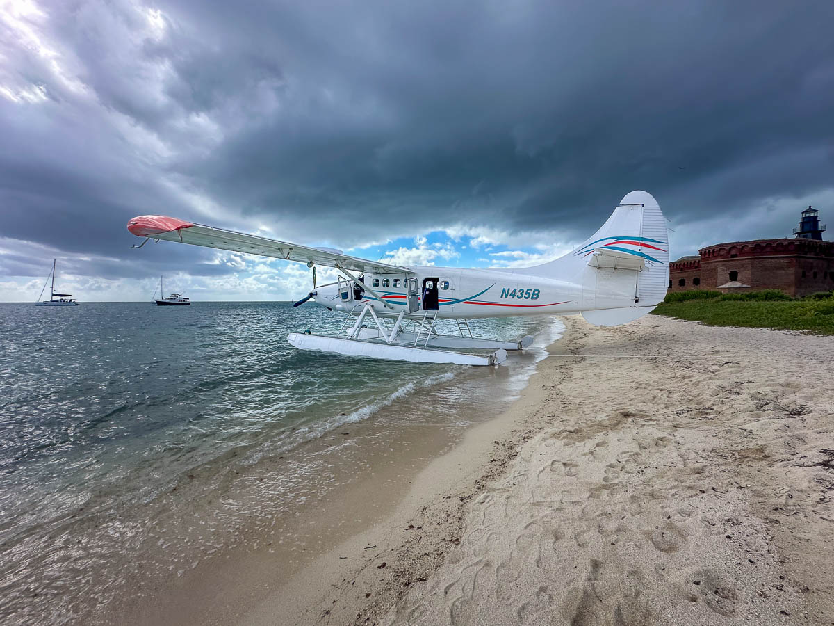 Sea plane from Key West Seaplane Adventures parked on a beach with Fort Jefferson in the background in Dry Tortugas National Park in Florida