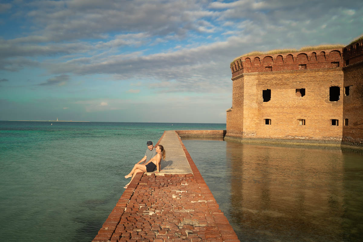 Couple sitting on a brick wall along a moat at Fort Jefferson at Dry Tortugas National Park off Key West, Florida