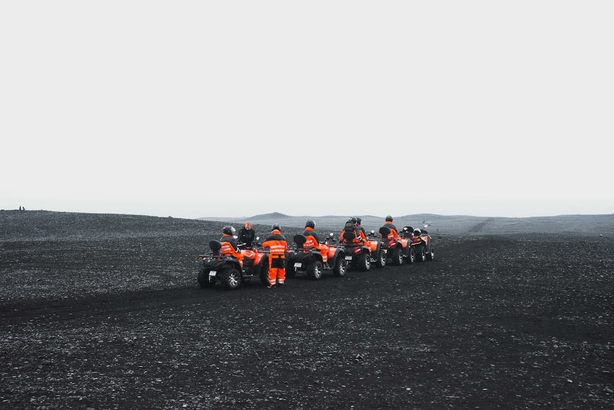 Group of ATVers driving on a black sand beach in Iceland