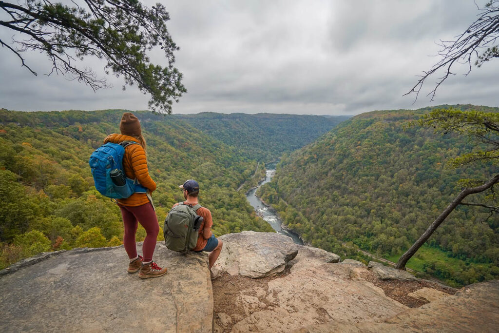 Couple sitting on a rocky outcropping at Diamong Point along the Endless Wall Trail overlooking the New River Gorge in New River Gorge National Park in West Virginia