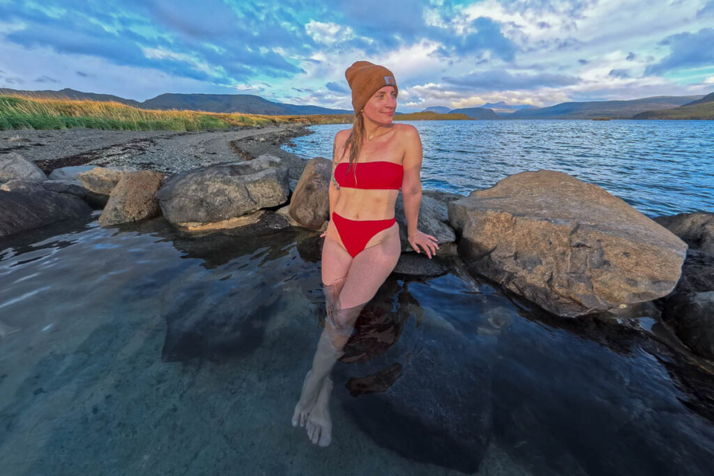Woman leaning against rocks in a pool in the Hvammsvik Hot Springs in Iceland