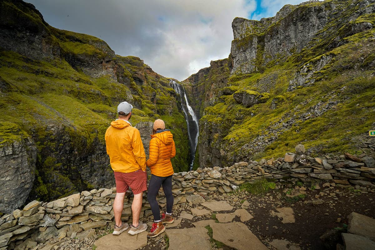 Couple standing at a rocky viewpoint overlooking the Glymur Waterfall in Iceland