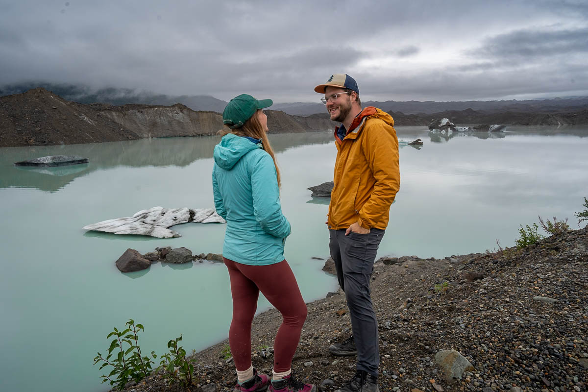 Couple standing in front of glacial lagoon at the toe of the Root Glacier in McCarthy, Alaska