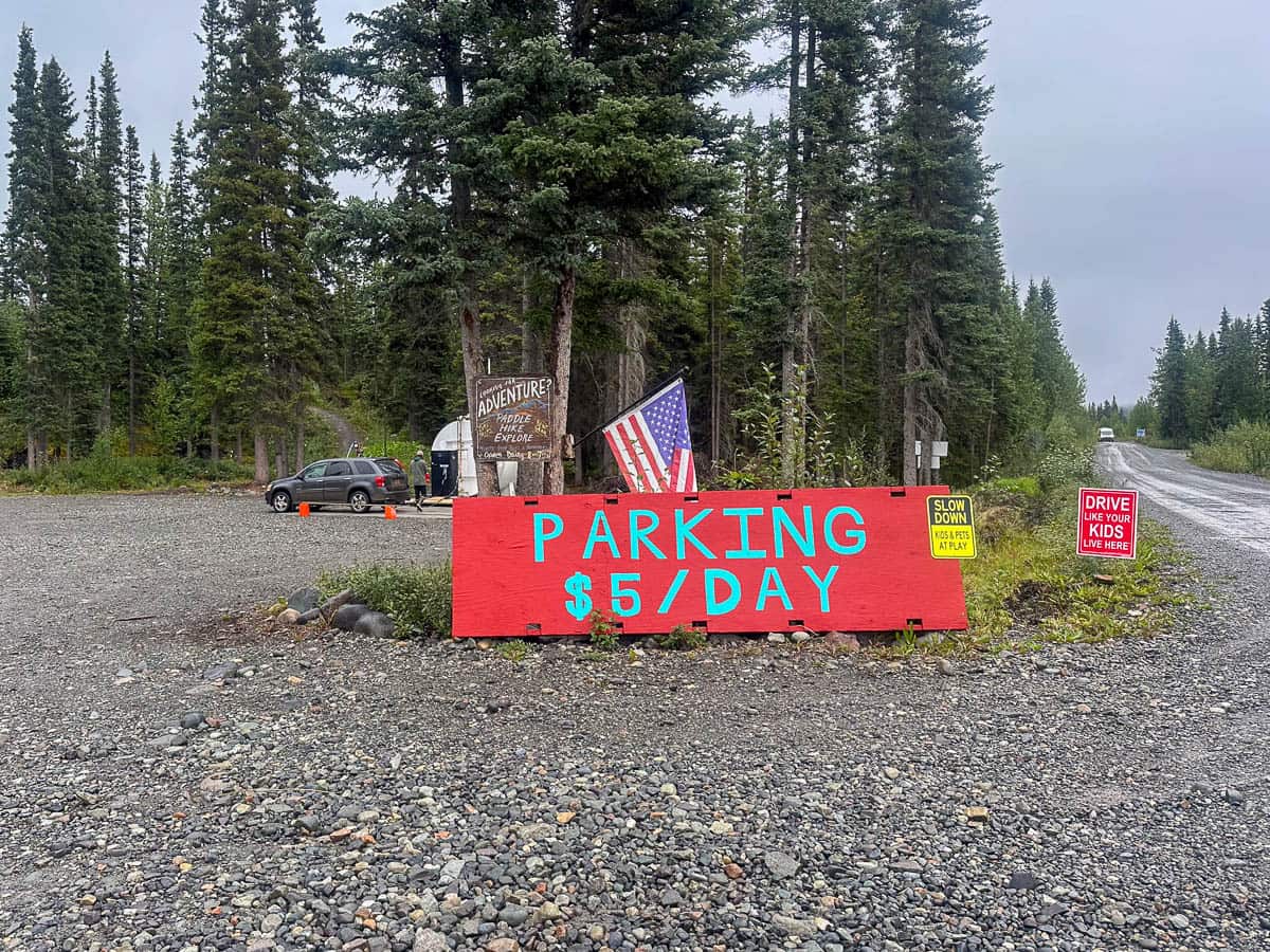 Sign for the parking at Base Camp Kennicott with pine trees in the background outside of McCarthy, Alaska