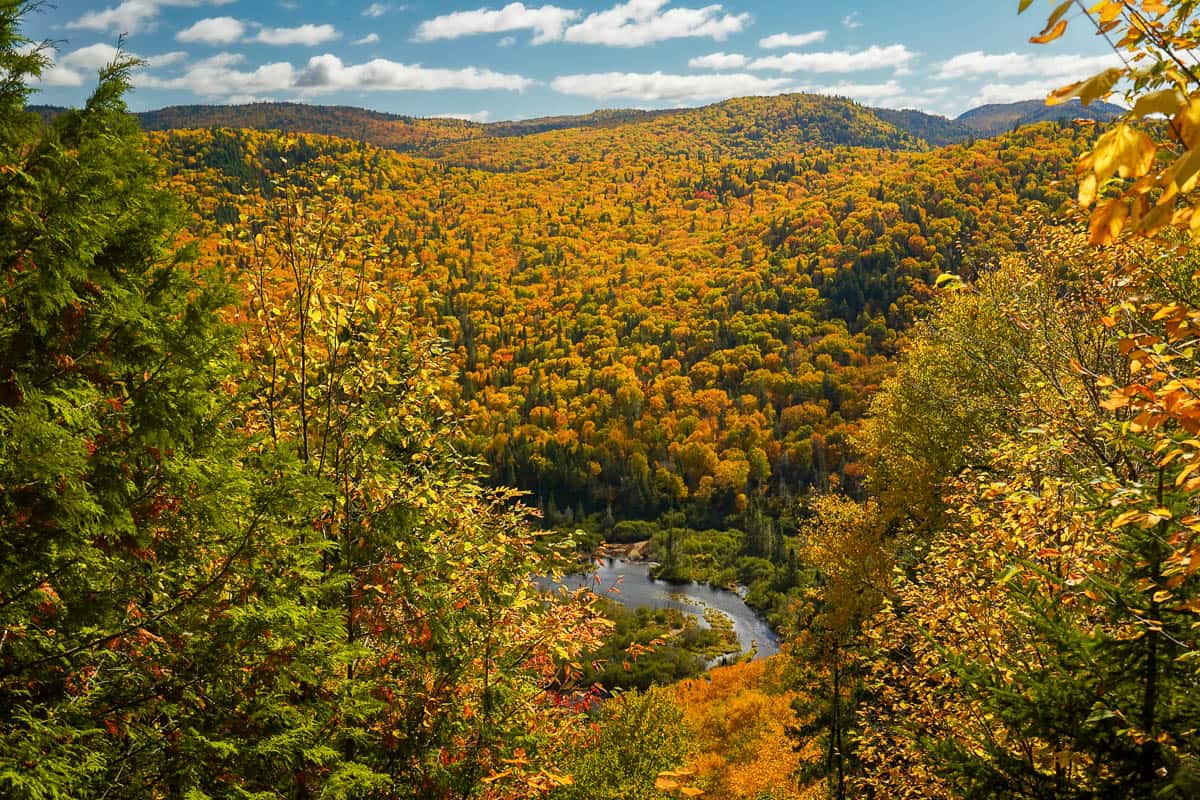 Rivière Jacques-Cartier surrounded by hills, covered by fall foliage, along the L'Eperon Trail in Jacques Cartier National Park in Quebec, Canada