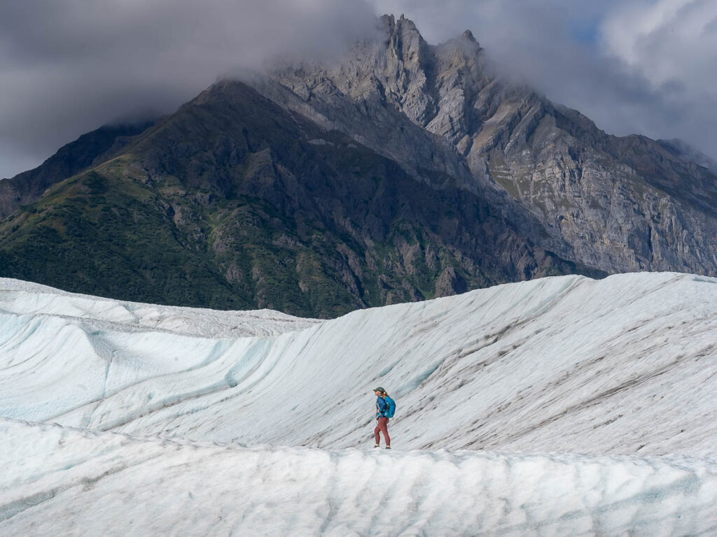 Woman hiking on the Root Glacier with a mountain in the background in Wrangell-St. Elias National Park