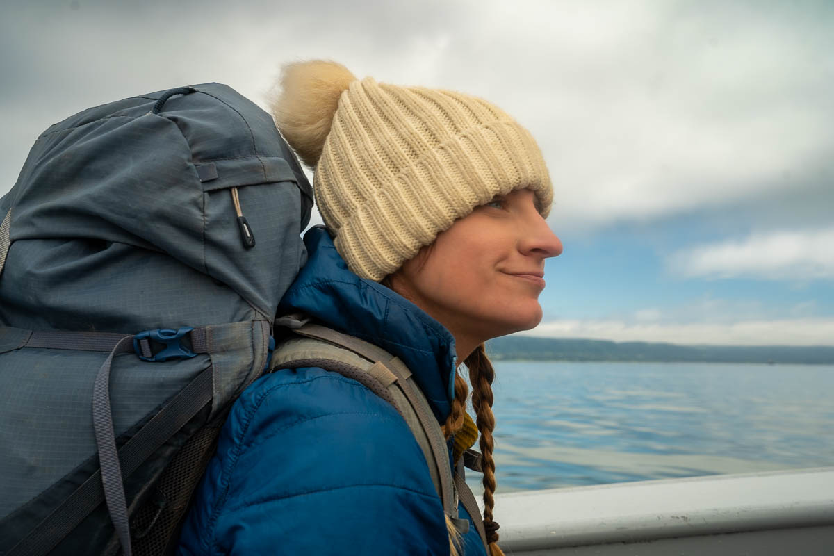 Woman wearing a backpack and hat on a water taxi to Kachemak Bay State Park in Alaska