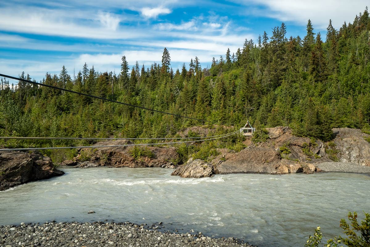 Tram over the Grewingk Creek with rugged cliffsides and pine trees in the background in Kachemak Bay State Park, Alasksa