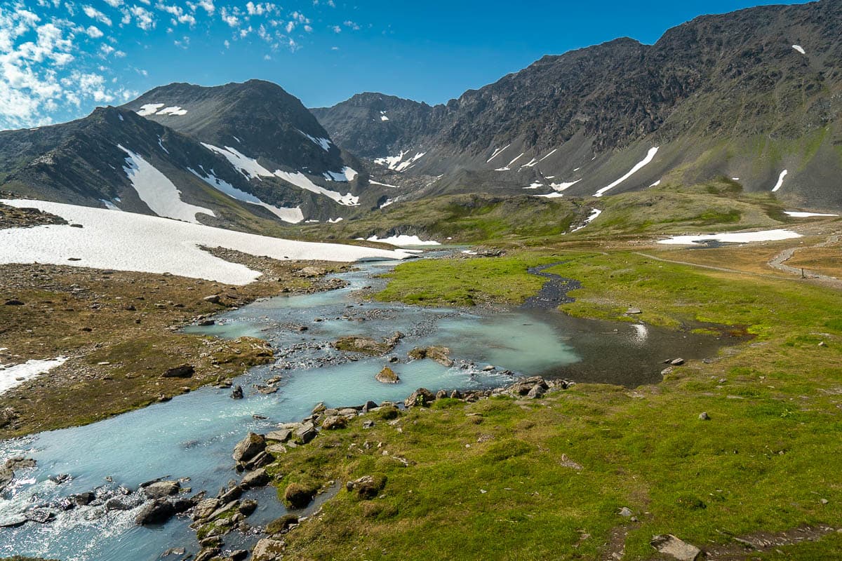 Milky turquoise stream with the Chugach Mountains in the background along the Crow Pass Trail in Chugach State Park in Anchorage, Alaska