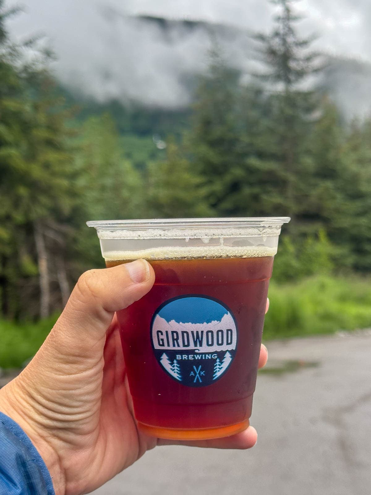 Woman holding a cup of beer at Girdwood Brewing in Girdwood, Alaska