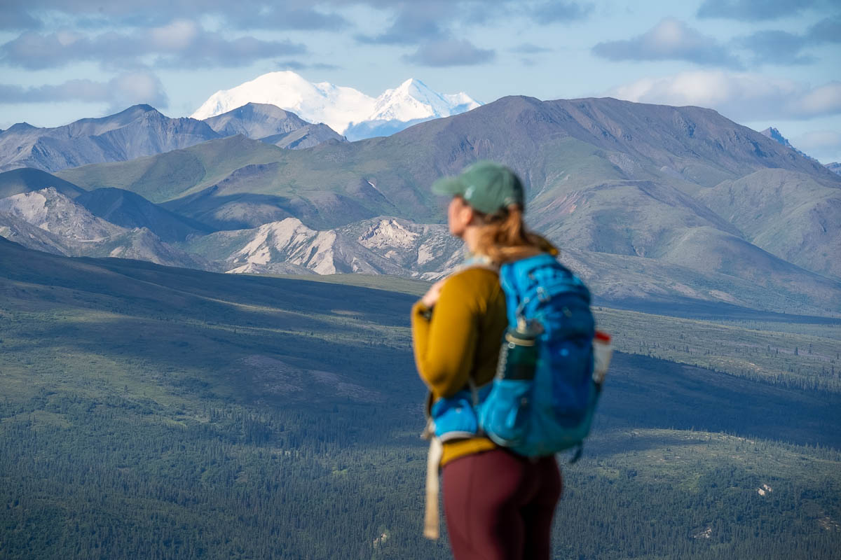 Woman looking at Mount Denali behind the Alaska Mountain range along the Mount Healy Overlook Trail in Denali National Park, Alaska