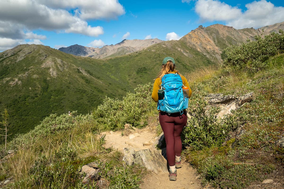 Woman walking along a pathway with the Alaska Mountain range in the background along the Mount Healy Overlook Trail in Denali National Park, Alaska