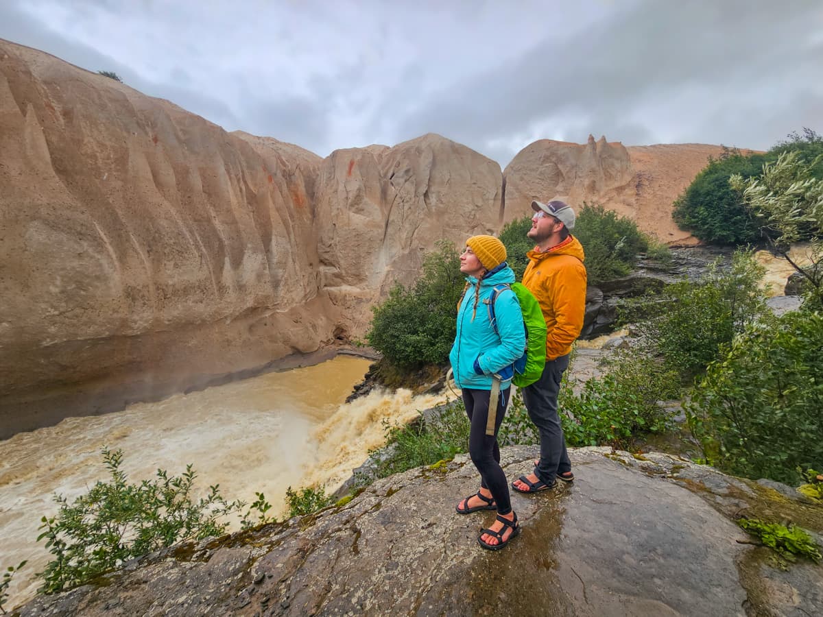 Couple standing on a rocky outcropping in the Valley of Ten Thousand Smokes on a rainy day in Katmai National Park, Alaska