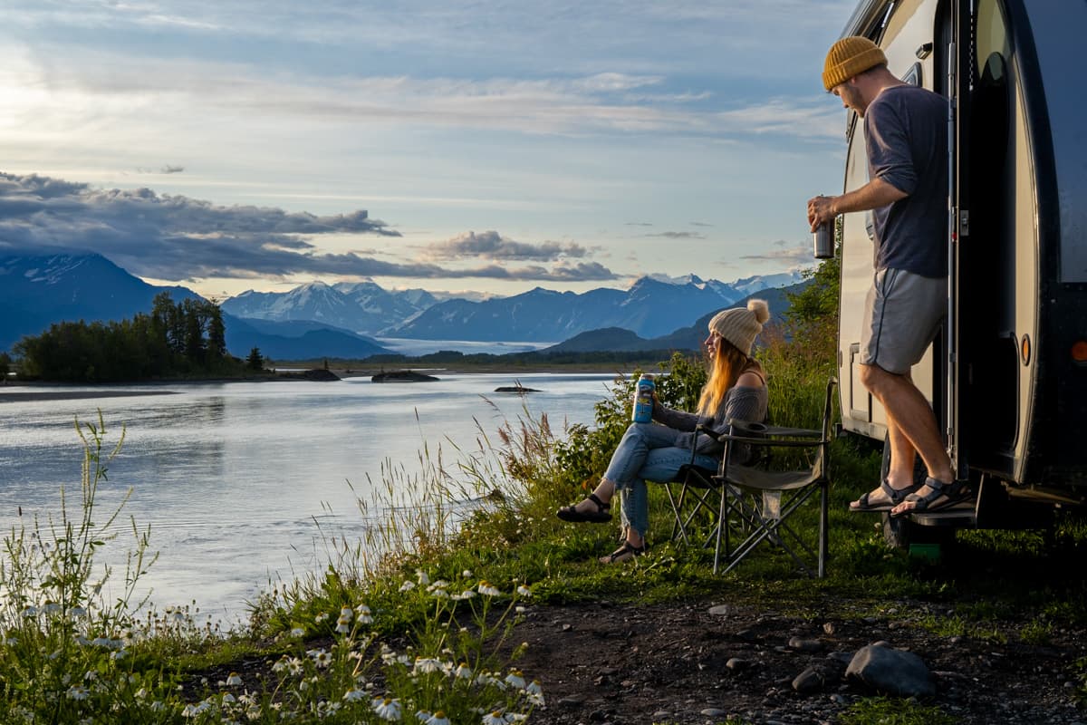 Couple sitting outside of a Safari Condo Alto F1743 Expedition next to the Knik Glacier in Palmer, Alaska