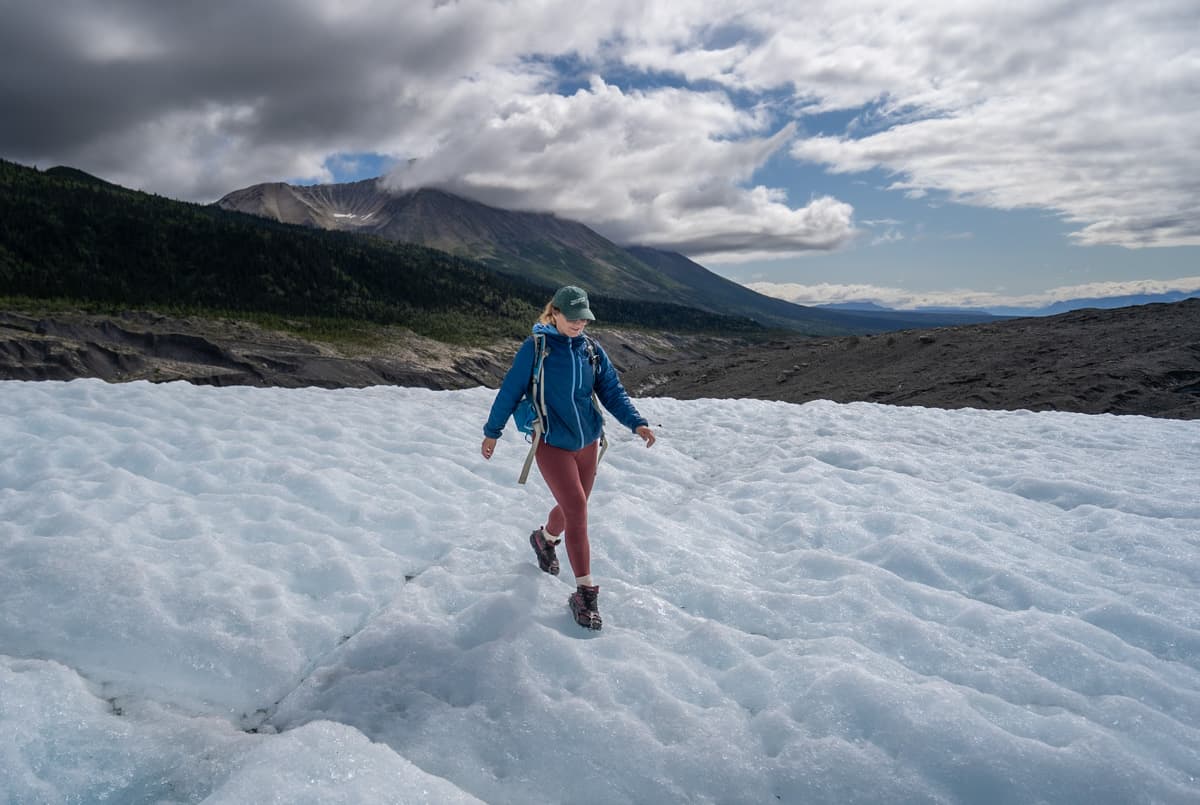 Woman walking on the Root Glacier with the Alaska Mountains in the background in Wrangell-St. Elias National Park, Alaska