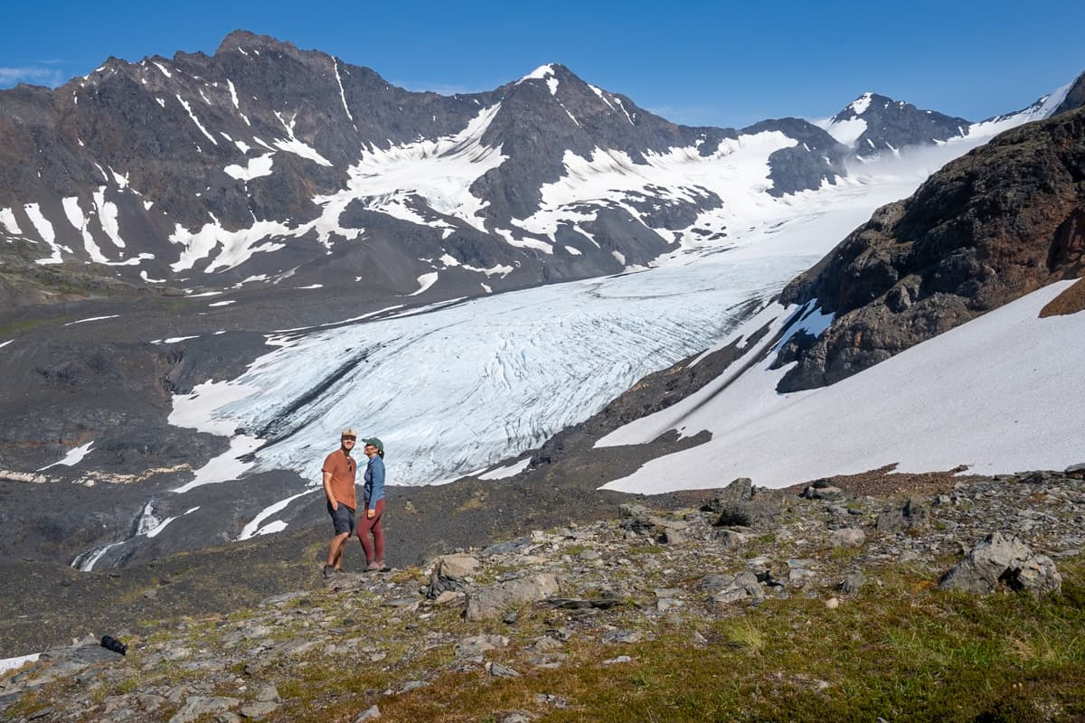 Couple standing in front of the Raven Glacier along the Crow Pass Trail in Chugach State Park in Alaska