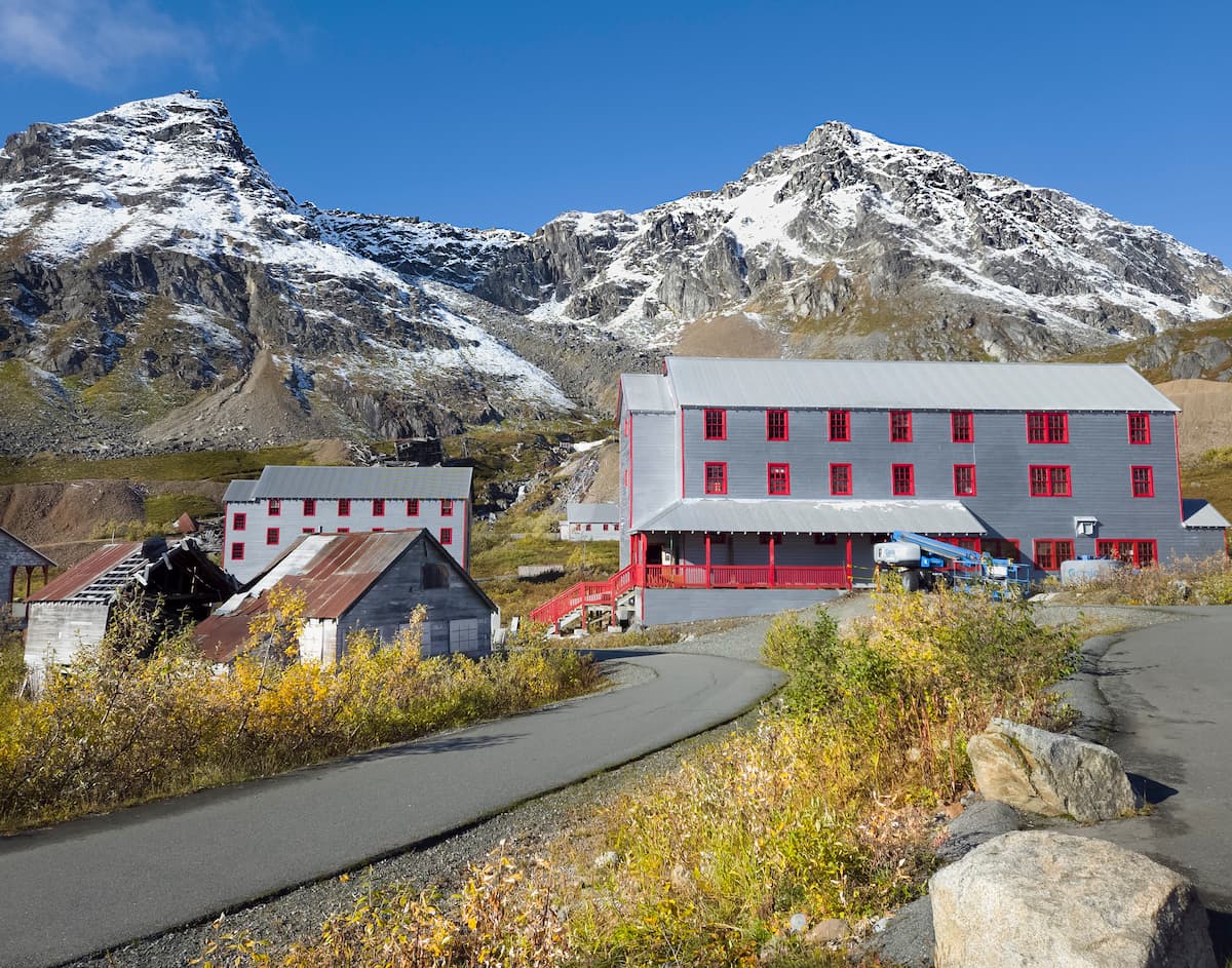 Buildings at the Independence Mine with the snowy Talkeetna Mountains in the background in the Independence Mine State Historical Park in Hatcher Pass, Alaska